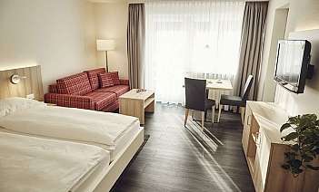 Helles Hotelzimmer mit Sitzbereich Gemütliches Hotelzimmer mit Bett, Sofa und Essbereich.