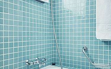 Moderne Badewanne mit Duschkopf und Handtuch.