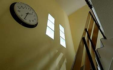 Interior view featuring a clock and staircase with natural light.