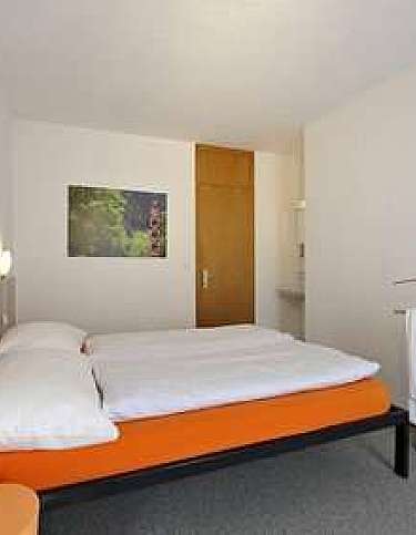 A simple hotel room with a double bed and towels.