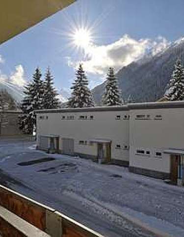 View of snow-covered buildings and trees in a mountainous area.