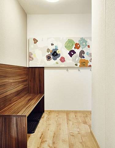 A stylish hallway featuring a wooden bench and colourful wall art.