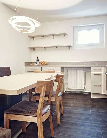 A sleek kitchen featuring a dining table and wooden chairs.