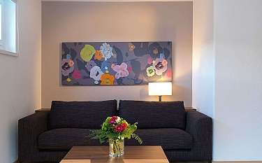 A stylish living room with a floral painting and a vase of flowers.