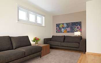 Helles Wohnzimmer mit zwei Sofas, Tisch und Blumenstrauß.