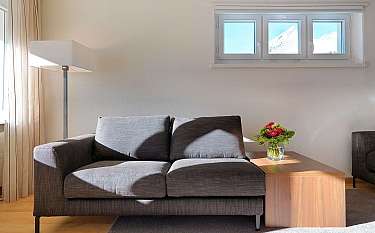 A stylish sofa with a wooden table and flowers in a bright room.