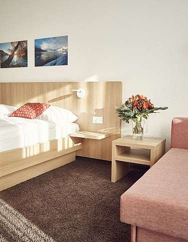 Gemütliches Hotelzimmer mit Doppelbett und Sitzbereich.