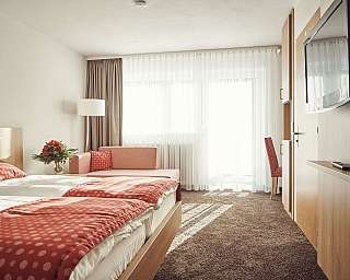 Gemütliches Hotelzimmer mit zwei Betten und einem Sofa.