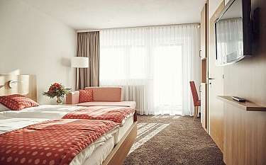 Ein modernes Hotelzimmer mit zwei Betten und einem Sofa.