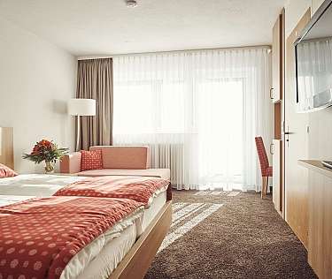 Gemütliches Hotelzimmer mit zwei Betten und einem Sofa.