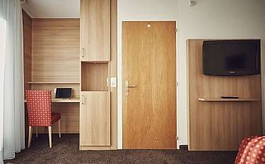 Ein schlichtes Hotelzimmer mit Holzregalen und einem Fernseher.