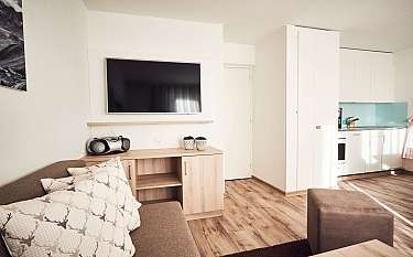 Modernes Wohnzimmer mit Fernseher und Küchenzeile.