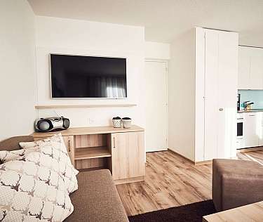 Modernes Wohnzimmer mit Fernseher und Küchenzeile.