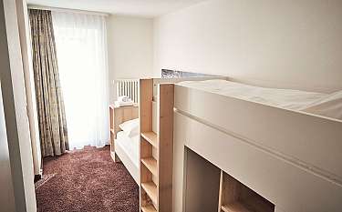 Ein modernes Zimmer mit einem Etagenbett und Fenster mit Vorhängen.