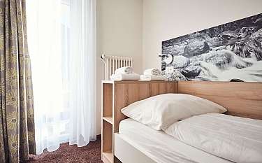 Ein einfaches Schlafzimmer mit Bett, Handtüchern und Fenster.