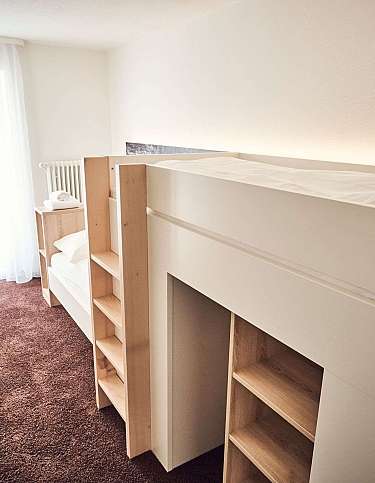 Helles Schlafzimmer mit Hochbett und Regalen aus Holz.