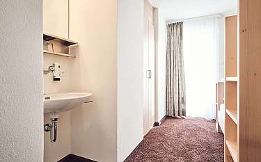 Ein Zimmer mit Waschbecken und Fenster mit Vorhängen.