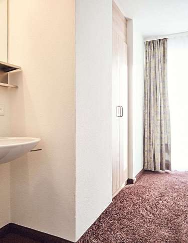 Ein Zimmer mit Waschbecken, Fenster und Teppichboden.