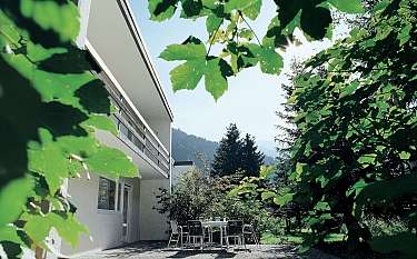 Ein modernes Gebäude mit einem Tisch und Stühlen im Garten.