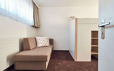 Ein einfaches Zimmer mit einem Sofa und einem weißen Raumteiler.