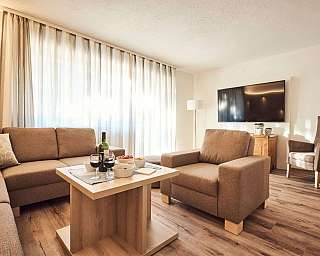 Helles Wohnzimmer mit Sofa, Tisch und Weinflasche.