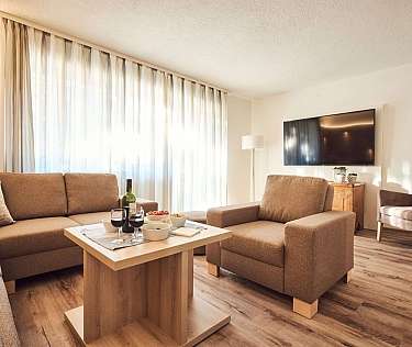 A stylish living room with a sofa, drinks, and a TV.