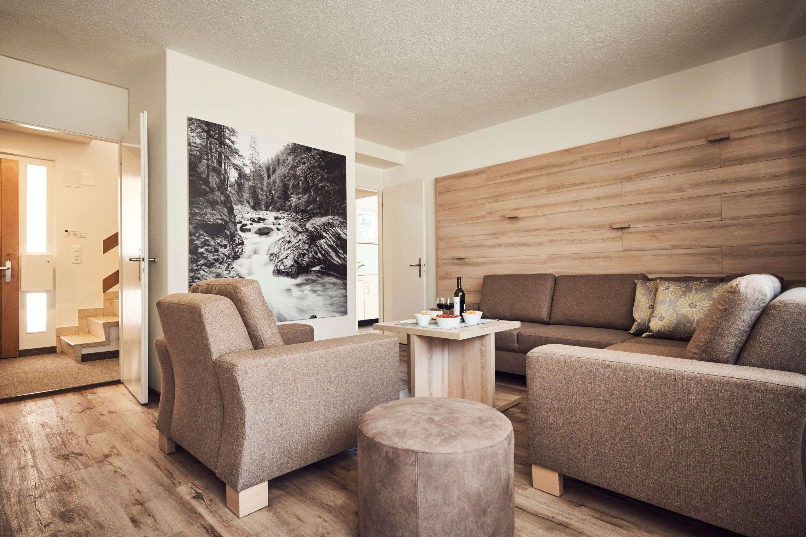 Gemütliches Wohnzimmer mit Sofas, Sessel, Couchtisch und großem Wandbild.