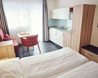 Modernes Zimmer mit Küchenzeile, Tisch und gemütlichen Sitzgelegenheiten.