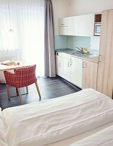 Modernes Hotelzimmer mit Küchenzeile und Essbereich.