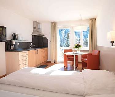 Bright hotel room with kitchenette and dining area.