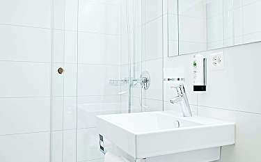 Helles Badezimmer mit Glasdusche und Waschbecken.