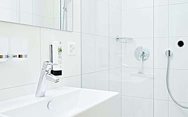 Helles Badezimmer mit Waschbecken und Glasdusche.